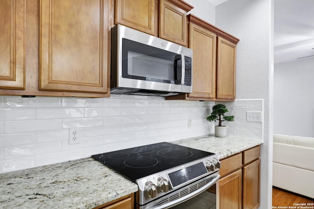 kitchen with appliances with stainless steel finishes, decorative backsplash, and light stone counters