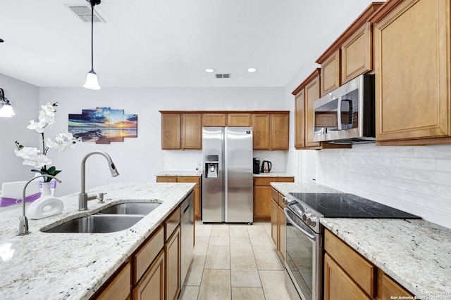 kitchen featuring backsplash, sink, hanging light fixtures, appliances with stainless steel finishes, and light stone counters