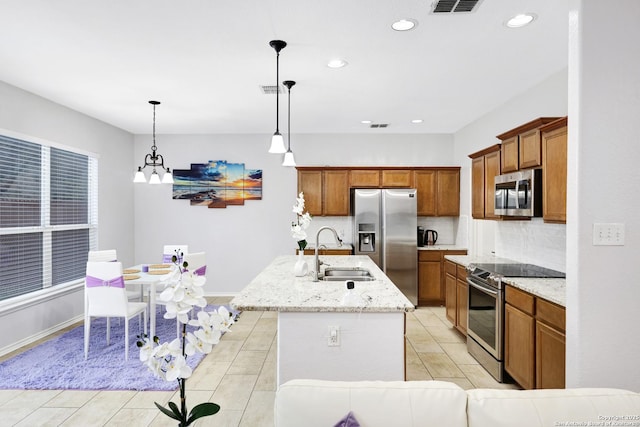 kitchen with appliances with stainless steel finishes, decorative light fixtures, decorative backsplash, sink, and a kitchen island with sink