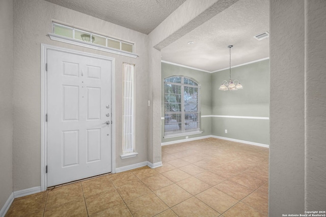 tiled foyer with crown molding, an inviting chandelier, and a textured ceiling