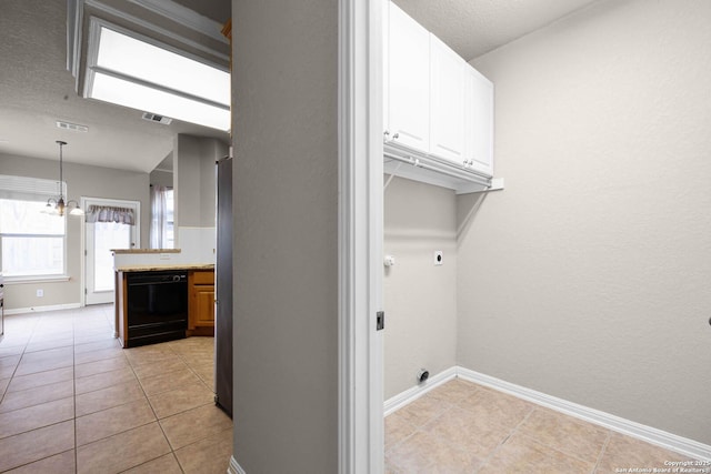 laundry room featuring electric dryer hookup, a textured ceiling, light tile patterned floors, a chandelier, and cabinets