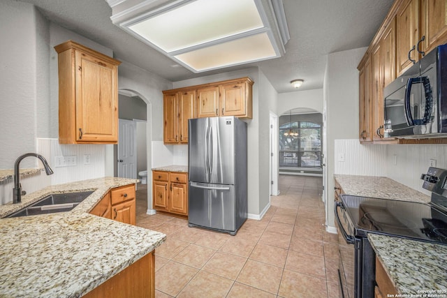 kitchen with black appliances, sink, a textured ceiling, light tile patterned floors, and light stone counters