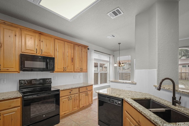 kitchen with black appliances, light stone countertops, sink, and a chandelier