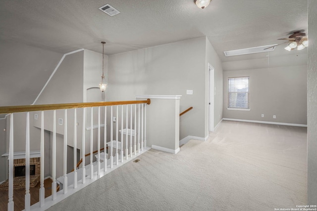 hall with a textured ceiling, carpet flooring, and lofted ceiling with skylight