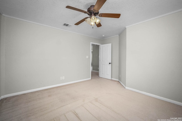 spare room featuring ceiling fan, light colored carpet, a textured ceiling, and crown molding