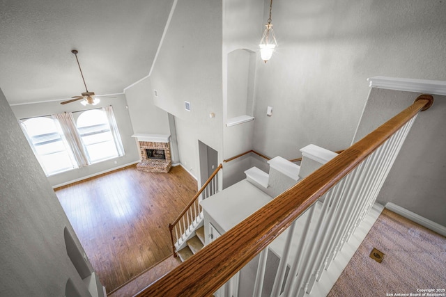 stairs with ceiling fan and a brick fireplace