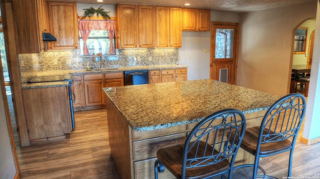 kitchen with dishwasher, sink, light hardwood / wood-style floors, and a kitchen island