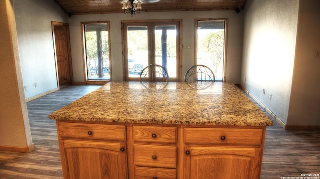 kitchen featuring light stone countertops, dark wood-type flooring, a center island, and wood ceiling