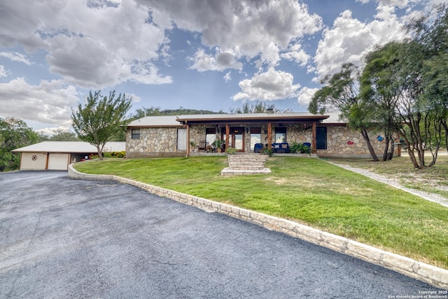 single story home featuring a garage, a front lawn, and an outbuilding