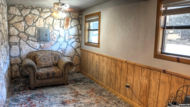 unfurnished room featuring a textured ceiling, electric panel, wood walls, and a healthy amount of sunlight