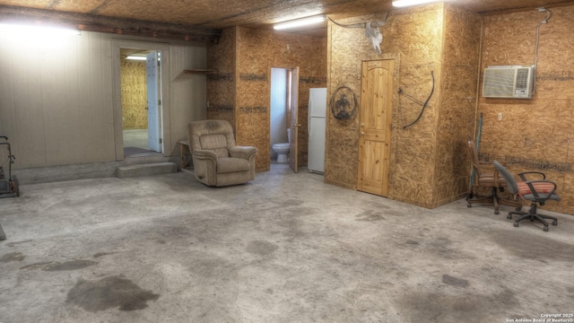 basement with white fridge and an AC wall unit