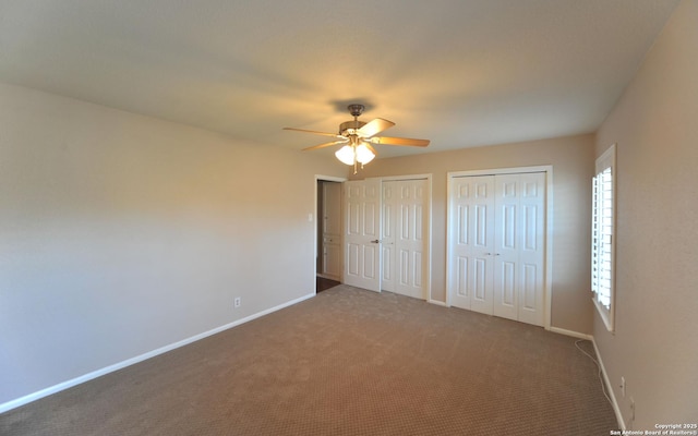 unfurnished bedroom with ceiling fan, carpet, and two closets