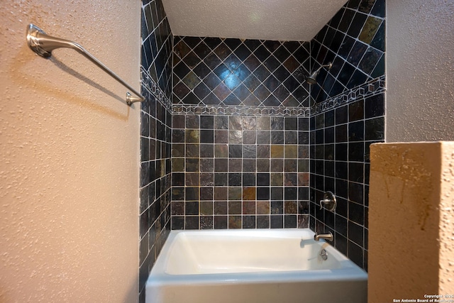 bathroom with a textured ceiling and tiled shower / bath