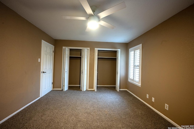 unfurnished bedroom with ceiling fan, carpet, and multiple closets