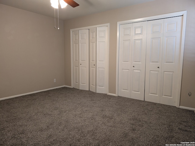 unfurnished bedroom with ceiling fan, multiple closets, and carpet flooring