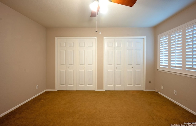 unfurnished bedroom featuring ceiling fan, two closets, and carpet floors