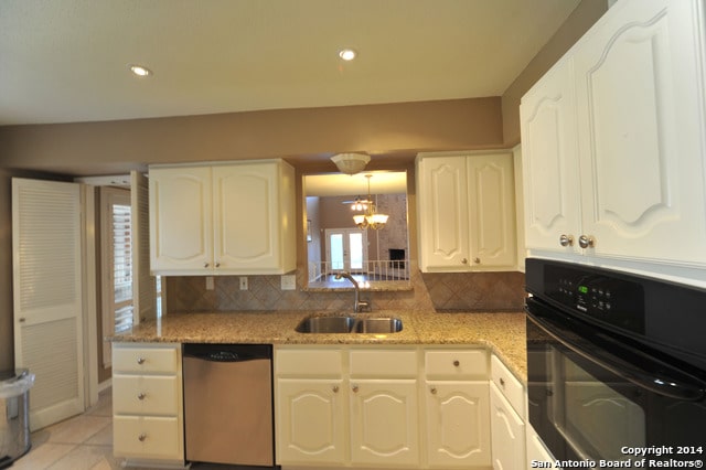 kitchen featuring white cabinetry, tasteful backsplash, sink, oven, and stainless steel dishwasher