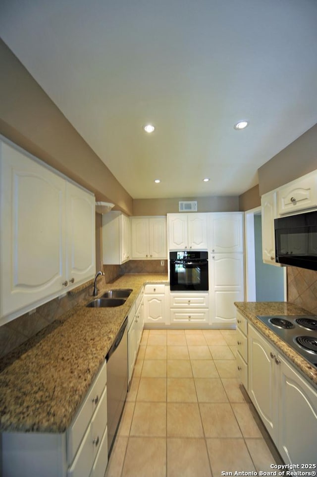 kitchen featuring white cabinets, black appliances, dark stone countertops, decorative backsplash, and sink