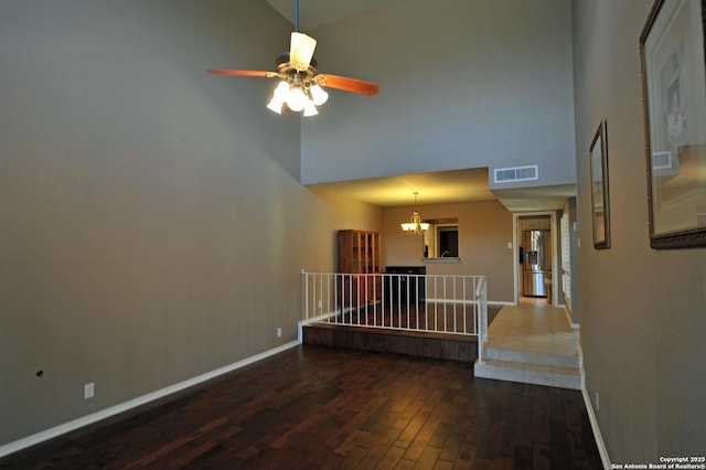 interior space featuring dark hardwood / wood-style flooring, a towering ceiling, and a notable chandelier