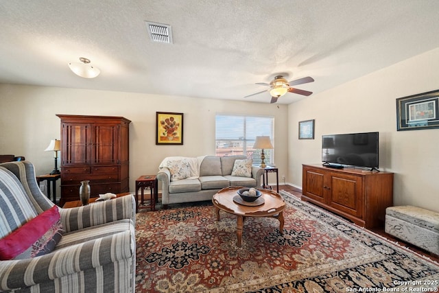 living room featuring ceiling fan and a textured ceiling