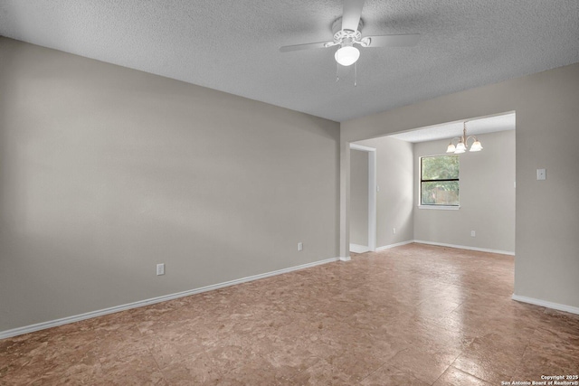 empty room with ceiling fan with notable chandelier and a textured ceiling