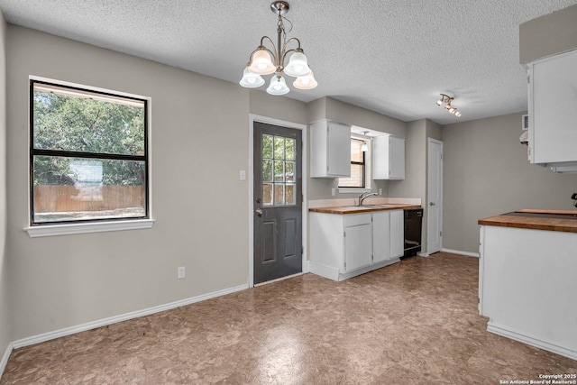 kitchen with white cabinets, wooden counters, a healthy amount of sunlight, and pendant lighting