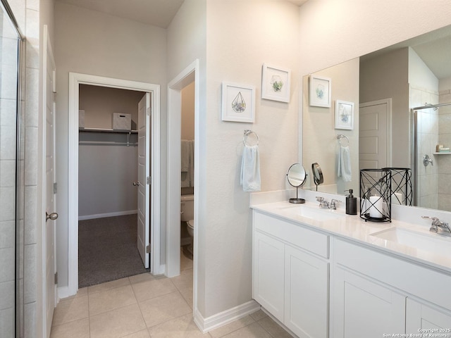 bathroom featuring tile patterned floors, a shower with door, toilet, and vanity