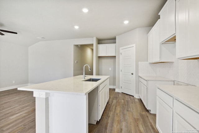 kitchen with light wood-type flooring, white cabinetry, a center island with sink, and sink