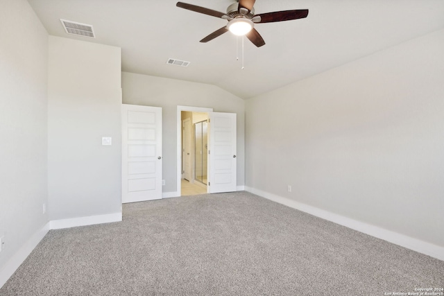 unfurnished bedroom with ceiling fan, light colored carpet, lofted ceiling, and ensuite bath