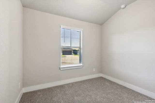 spare room featuring vaulted ceiling and carpet flooring