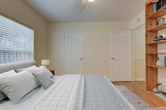 bedroom with light wood-style floors, baseboards, and a ceiling fan