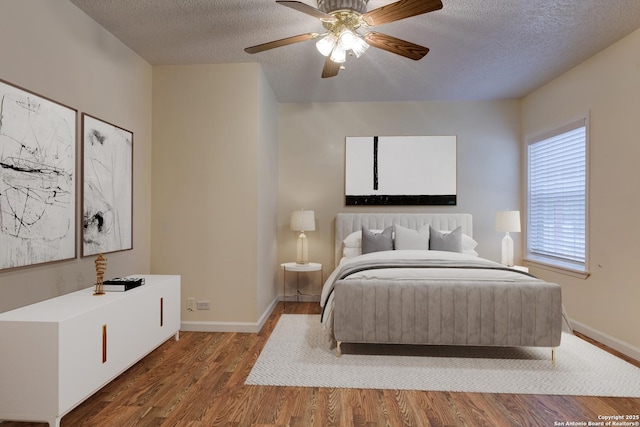 bedroom with a textured ceiling, ceiling fan, wood finished floors, and baseboards