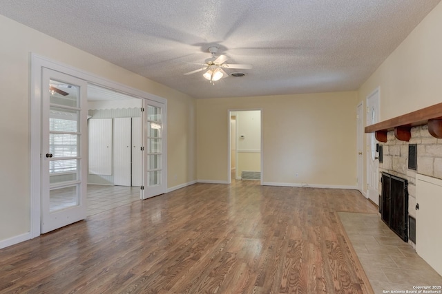 unfurnished living room with a ceiling fan, light wood-type flooring, and a fireplace