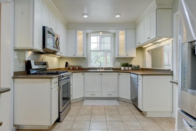 kitchen featuring light tile patterned floors, appliances with stainless steel finishes, glass insert cabinets, white cabinets, and a sink