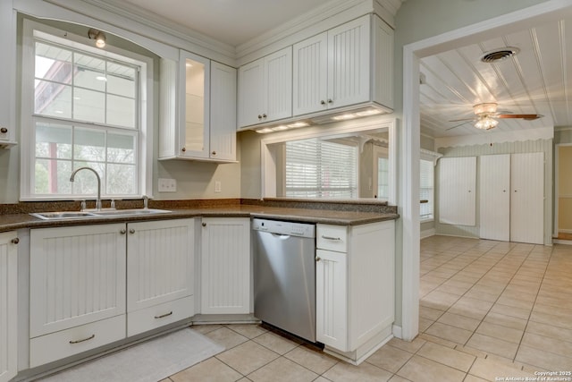 kitchen featuring light tile patterned floors, visible vents, dark countertops, stainless steel dishwasher, and a sink