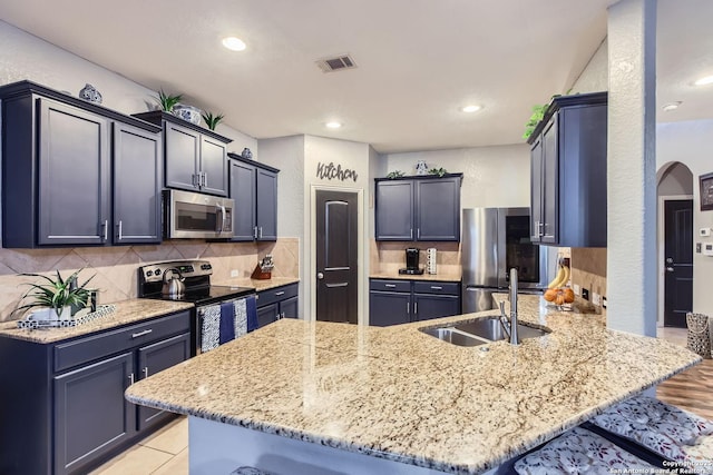 kitchen with a kitchen bar, kitchen peninsula, stainless steel appliances, tasteful backsplash, and light stone counters