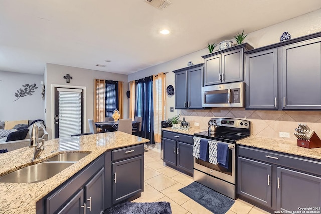 kitchen with stainless steel appliances, sink, backsplash, light stone counters, and light tile patterned floors