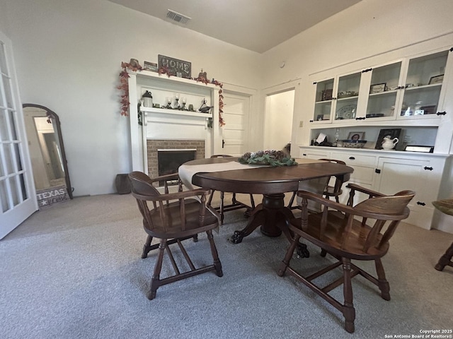 carpeted dining space featuring a brick fireplace