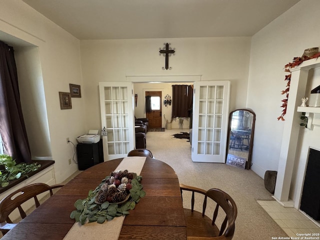 dining room with light carpet, french doors, and a fireplace