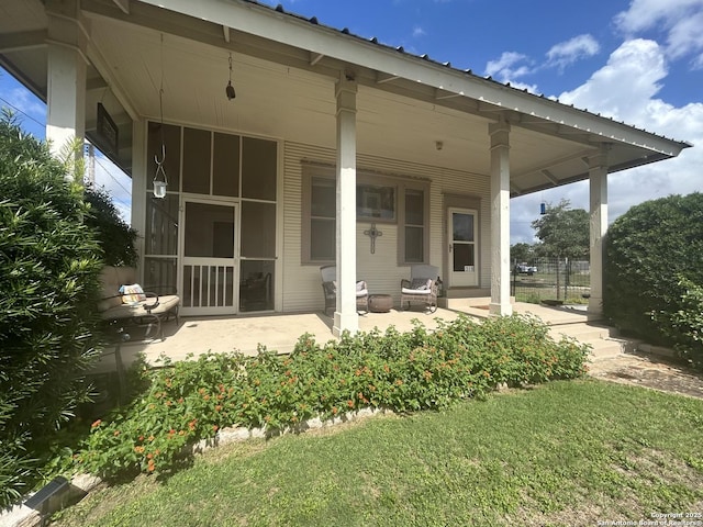 back of property featuring a patio area, a sunroom, and a lawn