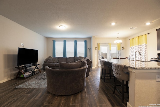 living room featuring sink, a textured ceiling, and a chandelier