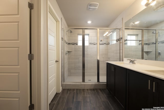 bathroom with a shower with shower door and vanity