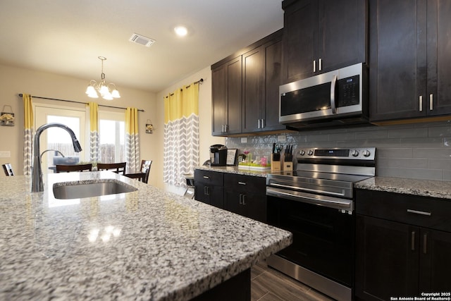 kitchen featuring tasteful backsplash, sink, light stone counters, and stainless steel appliances