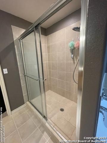 bathroom with tile patterned floors and a shower with door