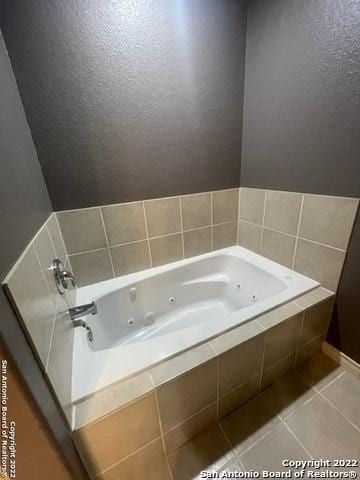 bathroom with tile patterned floors and tiled tub