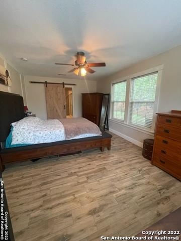 bedroom with ceiling fan, a barn door, and hardwood / wood-style floors