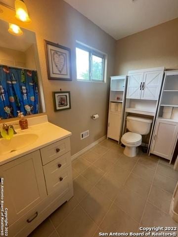 bathroom featuring toilet, vanity, and curtained shower