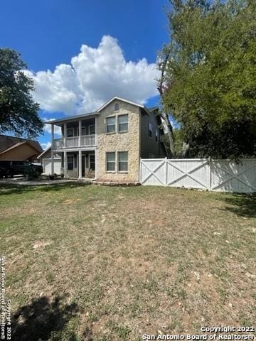 rear view of property with a balcony and a yard