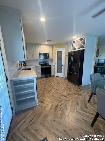 kitchen featuring black appliances, light parquet floors, sink, and white cabinetry