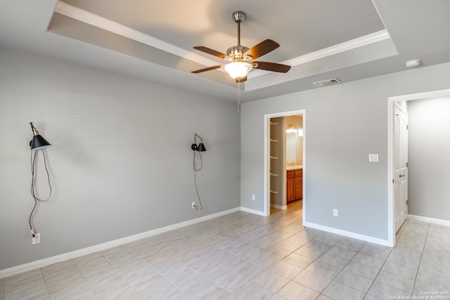 tiled empty room with ceiling fan, ornamental molding, and a raised ceiling